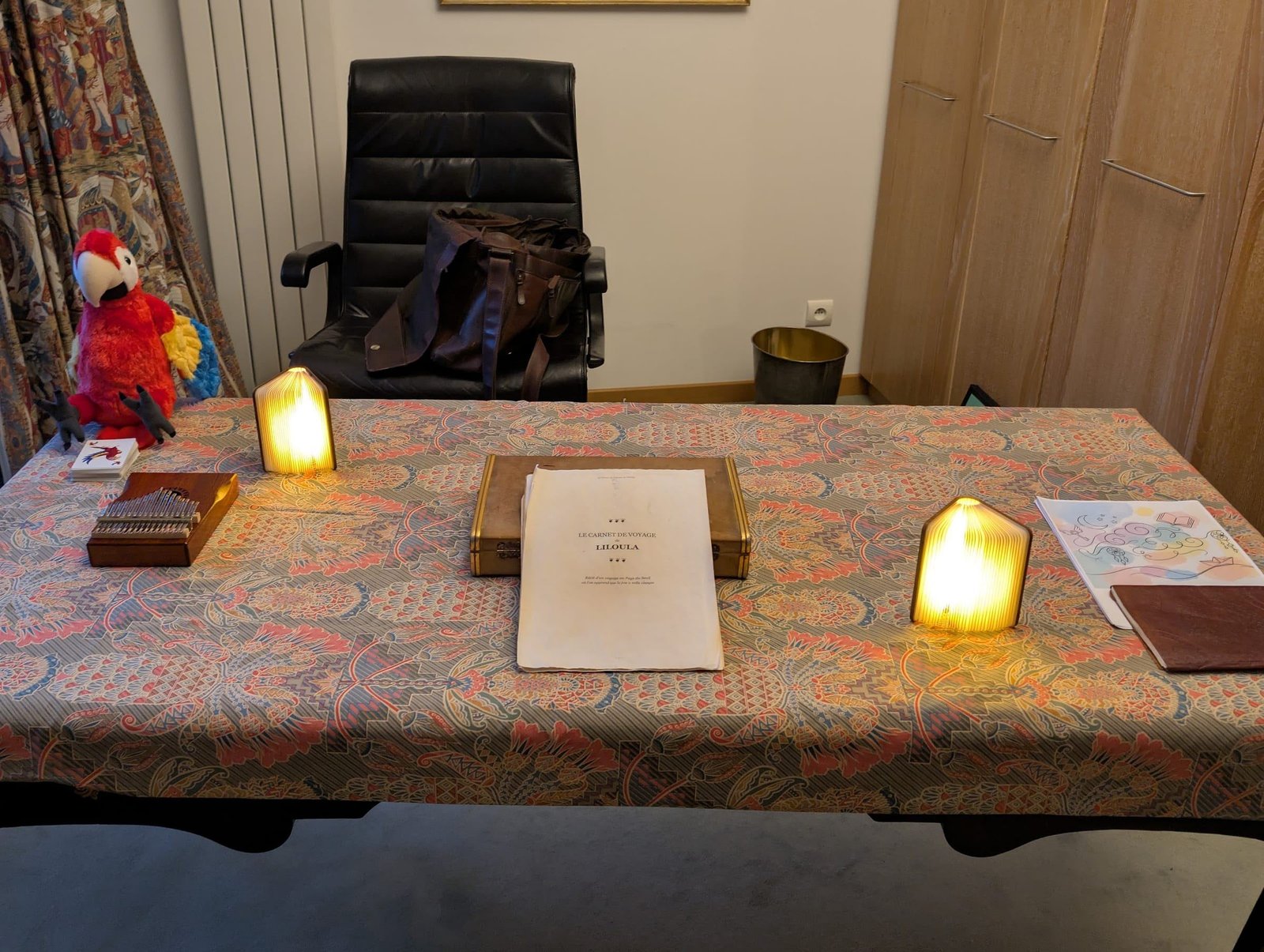 La table du spectacle avant l'arrivée des enfants : le perroquet en peluche, le kalimba, les livres-lumières et le carnet de voyage de Liloula