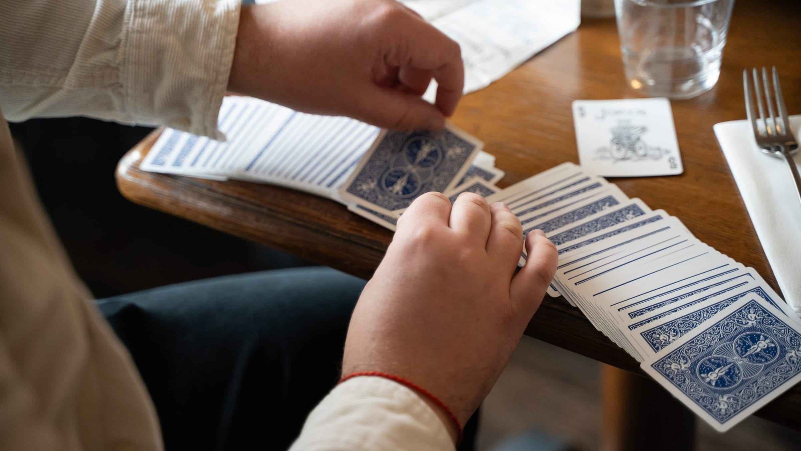 Les mains d'un spectateur et de Yannis Trophardy au-dessus d'un éventail de cartes, dans une lumière claire
