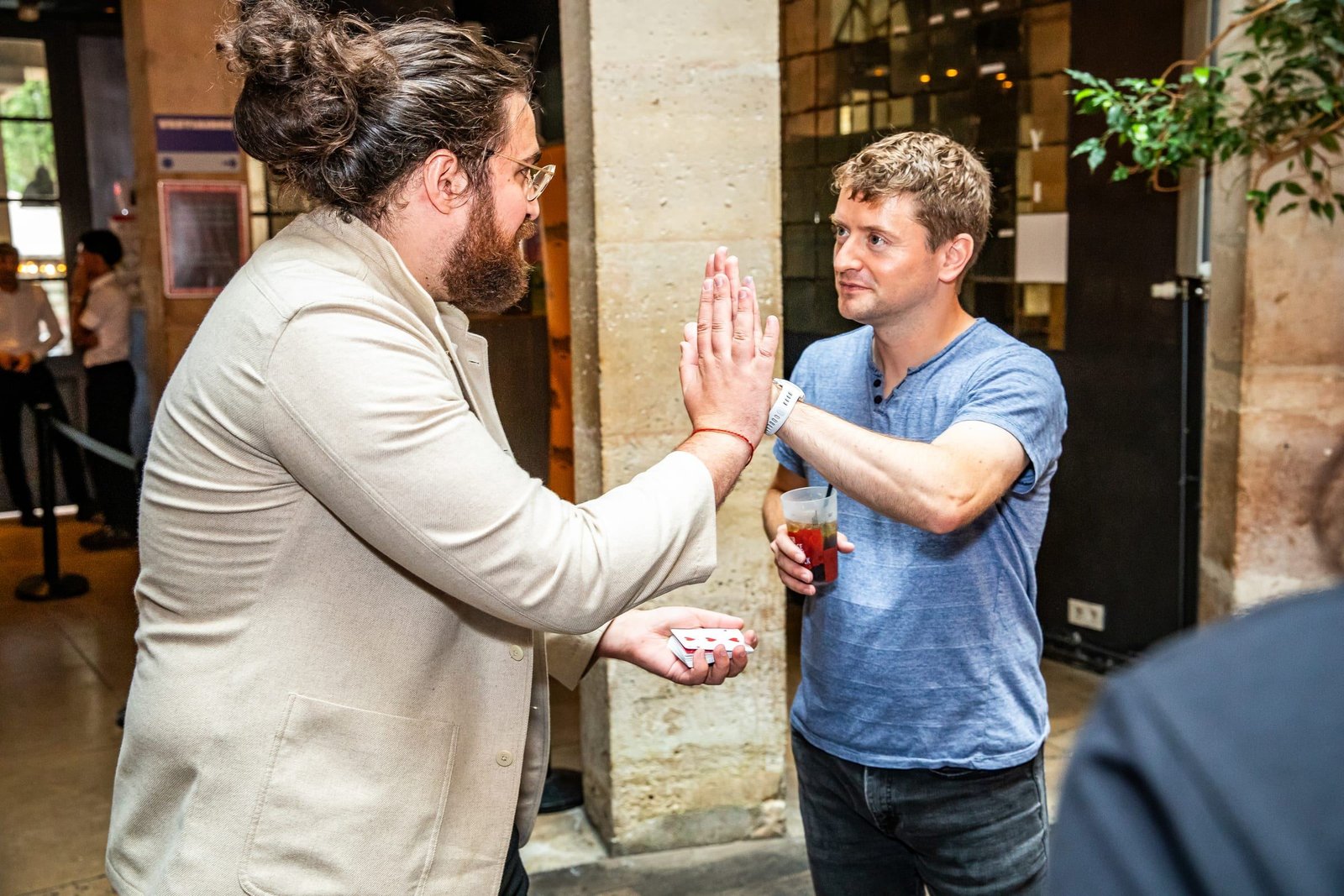 Un high-five entre Yannis Trophardy et un spectateur, cartes en main